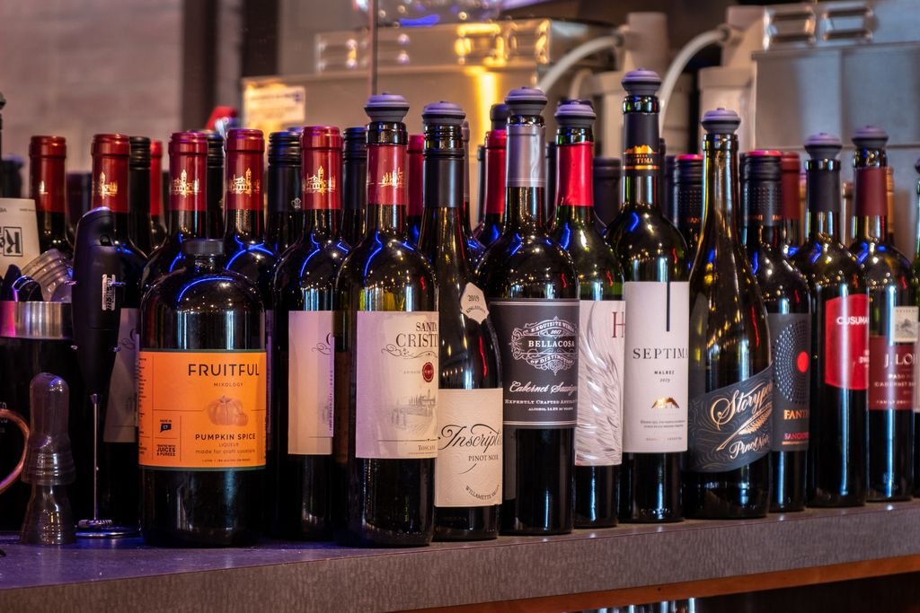 A variety of wine bottles elegantly displayed at a bar, including red, white, and sparkling wines.